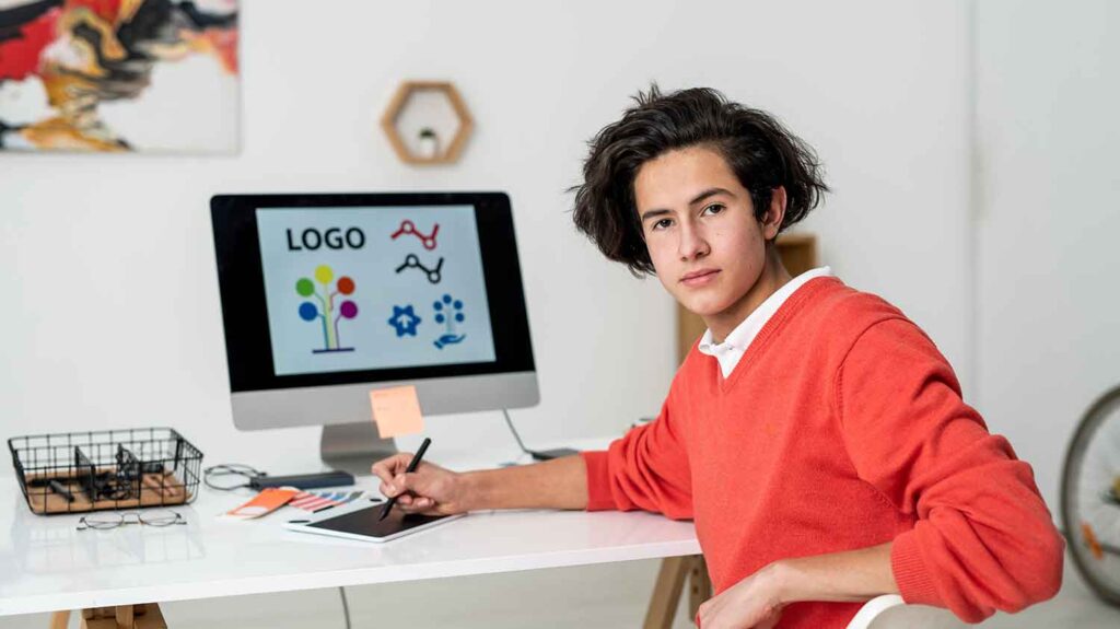 young serious boy looking at camera behind his desk 