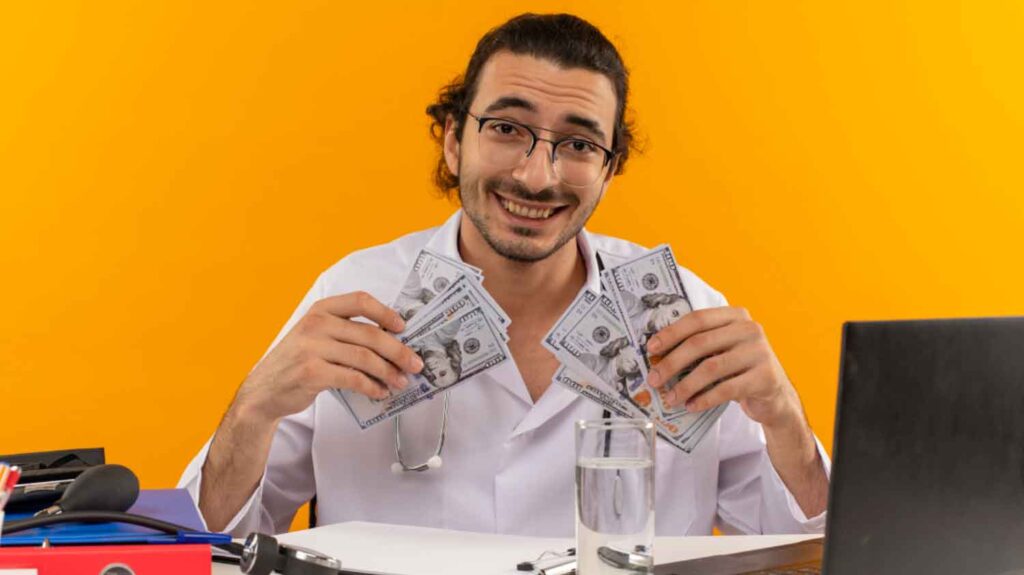 a man in front of his laptop holding money on both hands